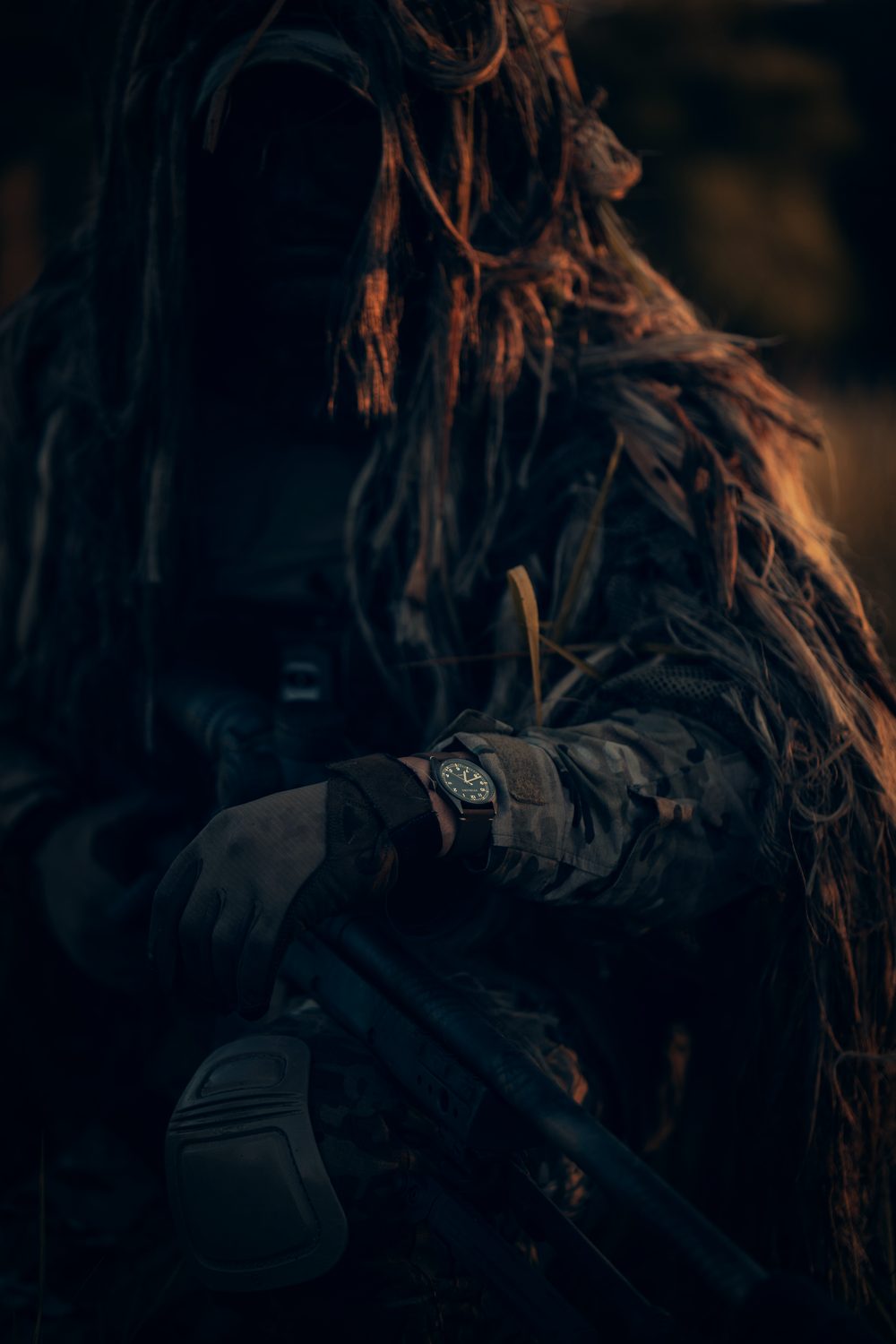Operator in a ghillie suit, low light.